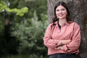 an image of a girl smiling and leaning against a tree