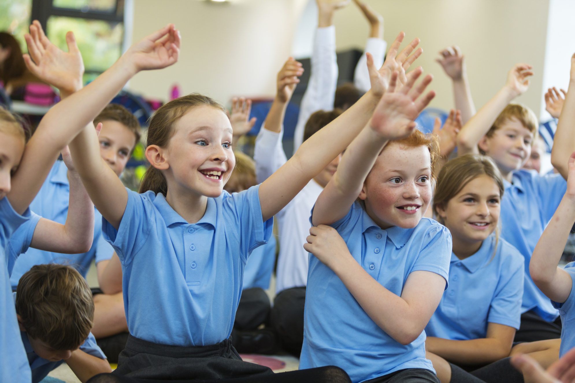 Excited School Children in Uniform with Hands Up